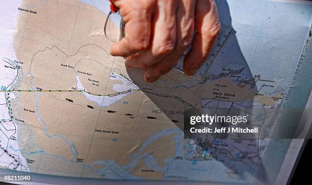 Man holds a map as pilgrims walk with crosses as the Northern Cross pilgrimage makes its final leg of the journey to Holy Island on April 2, 2010 in...
