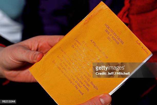 Woman holds a song book as pilgrims walk with crosses as the Northern Cross pilgrimage makes its final leg of the journey to Holy Island on April 2,...