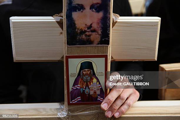 Christian pilgrim holds a wooden cross bearing icons of Jesus and Saint John of Shanghai and San Francisco during the Good Friday procession along...