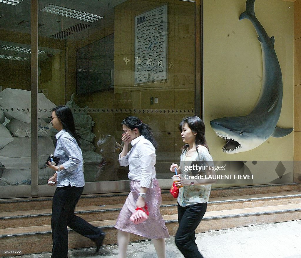 Office workers walk past a shark fin wha
