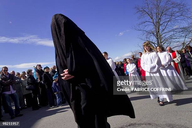 Mourner dressed in black stands in front of penitents during the traditionnal Good Friday celebration on April 2, 2010 in Romont. The ceremony begins...