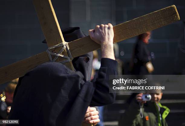 Mourner dressed in black carries a cross during the traditional Good Friday celebration on April 2, 2010 in Romont. The ceremony begins with a...