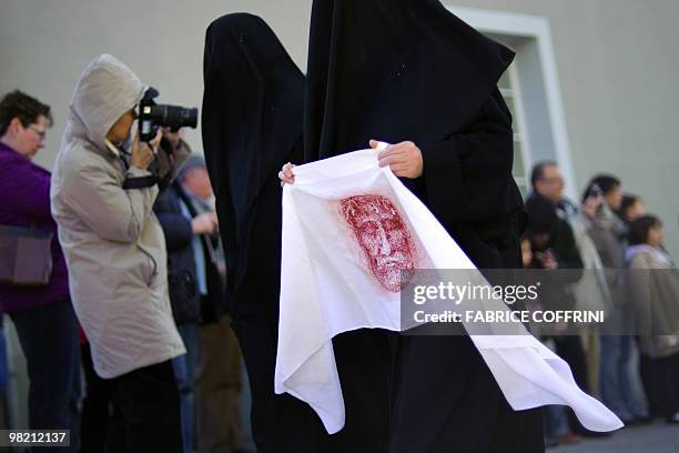 Mourner dressed in black holds a portrait of the Christ during the traditional Good Friday celebration on April 2, 2010 in Romont. The ceremony...