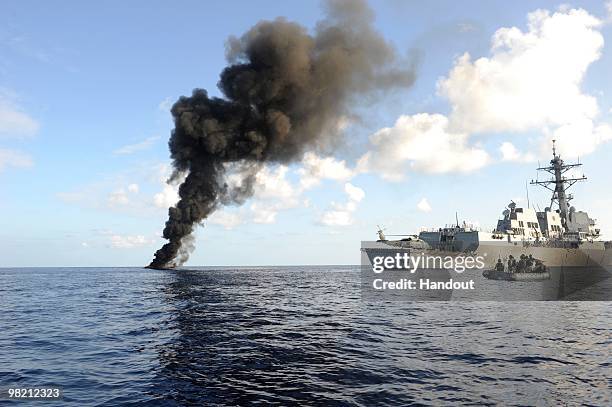 In this handout from the U.S. Navy, The Arleigh Burke-class guided missile destroyer USS Farragut passes by the smoke from a suspected pirate skiff...