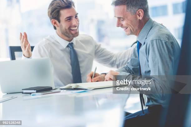 2 businessmen smiling and happy in a meeting. - mature men laughing stock pictures, royalty-free photos & images