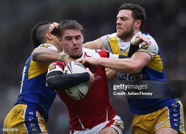 Ashley Gibson of Salford is tackled by Ryan Atkins and Simon Grix of Warrington during the Engage Super League match between Warrington Wolves and...