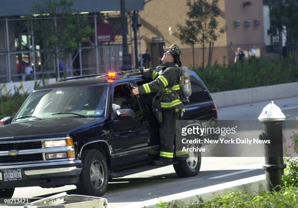 World Trade Center - Firefighter Brian Bilcher of Squad 1 rides on the outside of a vehicle driven by Akiva Flaum of Borough Park, who is also a...