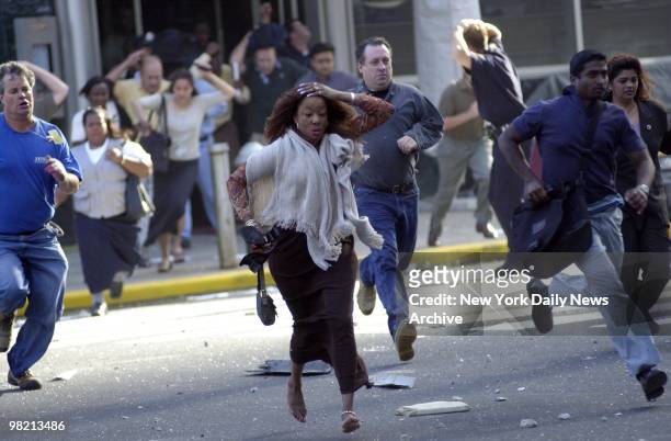 People scramble for cover under a shower of debris after the World Trade Center is struck in a terrorist attack on September 11, 2001 in New York...