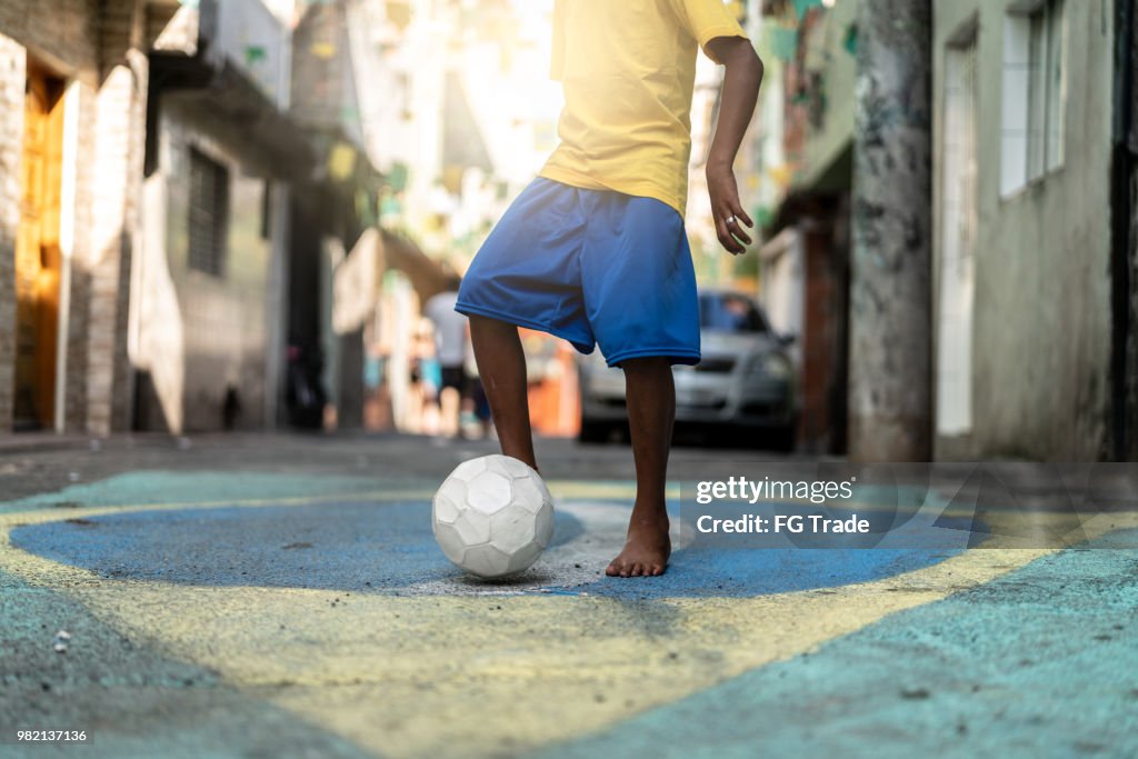 Close up of a Brazilian Kid Playing Soccer in the Street
