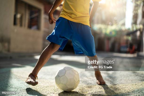 brazilian kid playing soccer in the street - brazilian culture stock pictures, royalty-free photos & images