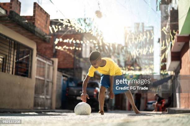 brazilian kid playing soccer in the street - poor kids playing soccer stock pictures, royalty-free photos & images