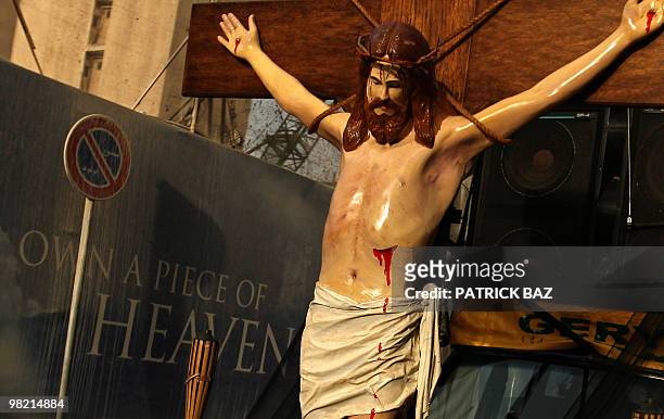 Statue of crucified Jesus Christ is driven past an advertising billboard for a real estate agency during the Good Friday procession in Beirut's...