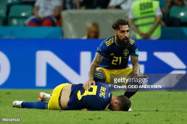 Sweden's midfielder Jimmy Durmaz helps his teammate Sweden's forward Marcus Berg laying on the football pitch after being injured during the Russia...