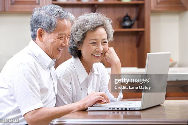 senior adults using laptop - luxury home dining table people lifestyle photography people stock pictures, royalty-free photos & images