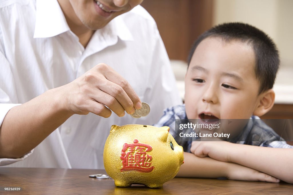 Father and son saving coins into a piggy bank