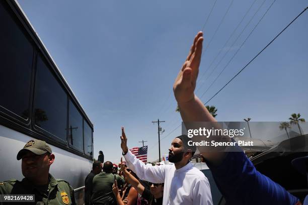 Protesters against the Trump administration's border policies wave and blow kisses to migrant children on a bus at a U.S. Customs and Border...