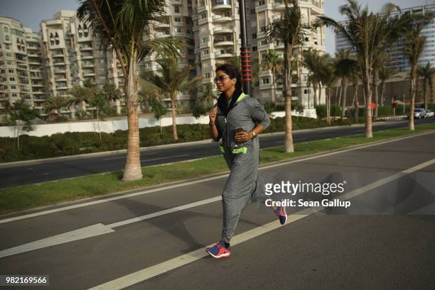 Raghda Safdar a university administrator and a divorced mother of three, runs wearing an abaya designed specifically for sports on a bicycle road...
