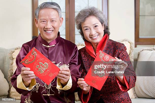 senior couple holding chinese new year red envelop - stereotypically upper class stock pictures, royalty-free photos & images