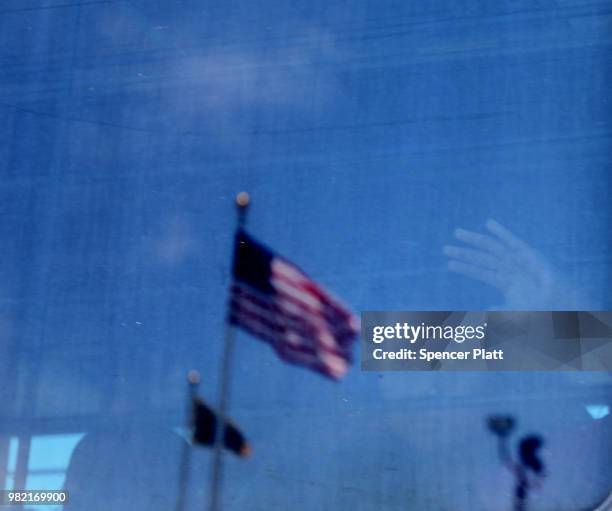 Migrant child looks out the window of a bus as protesters try to block a bus carrying migrant children out of a U.S. Customs and Border Protection...