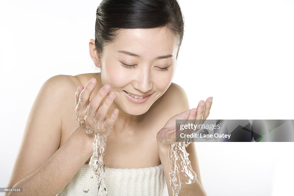 Beautiful young woman washing face
