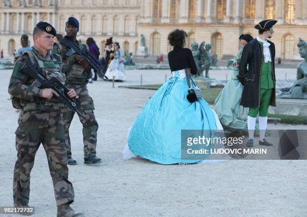 French soldiers patrol while people wearing period costumes take part in a masked ball at Versailles castle, near Paris, on June 23, 2018