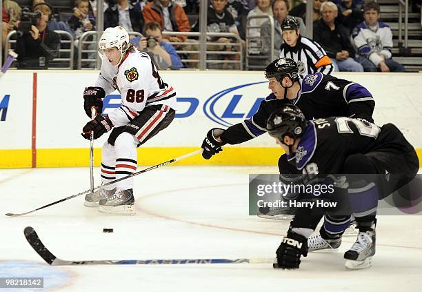 Patrick Kane of the Chicago Blackhawks passes the puck as he is watched by Rob Scuderi and Jarret Stoll of the Los Angeles Kings at the Staples...