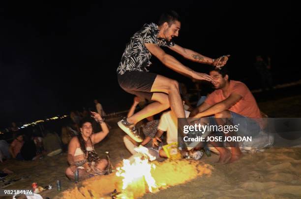 Man jumps over a bonfire during the annual San Juan celebrations on a beach in Alicante on June 23, 2018. - Fires are lit throughout Spain on the Eve...