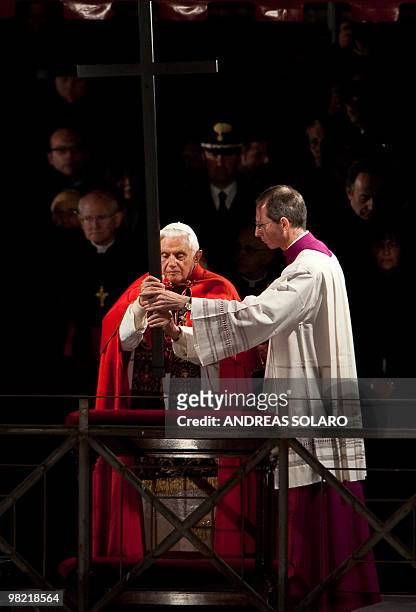 Pope Benedict XVI is presented the Cross during the Way of the Cross on Good Friday on April 2, 2010 at Rome's Colosseum. AFP PHOTO / ANDREAS SOLARO