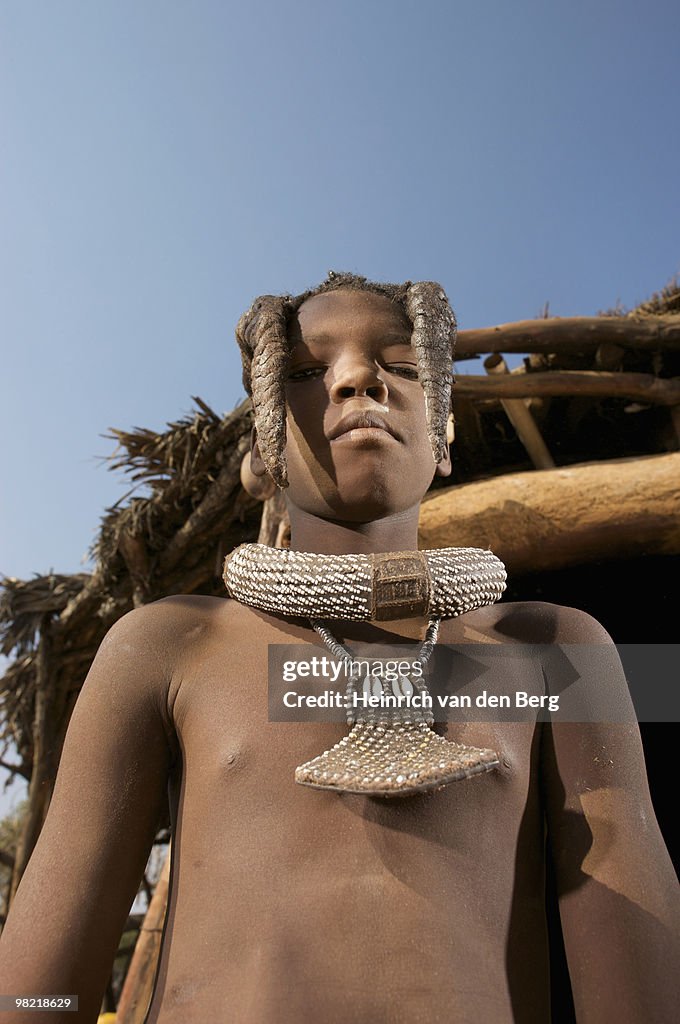 Low angle view of a Himba teeanage boy looking at camera, Epupa Falls area, Kaokoland, Namibia