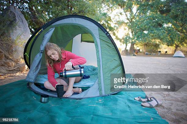 young woman relaxing in tent pouring a cup of coffee, van zylâ��ã�ã´s pass area, kaokoland, namibia - freek van den bergh stock pictures, royalty-free photos & images