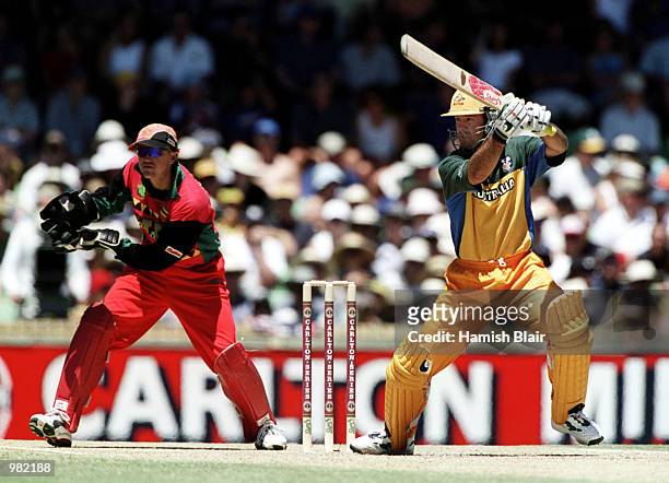 Ricky Ponting of Australia drives through cover point during his innings of 32 as wicketkeeper Andy Flower of Zimbabwe looks on during the Carlton...
