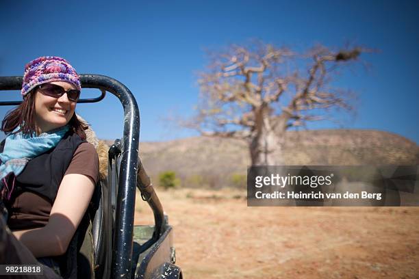 young woman sitting in motor vehicle with baobab tree in background, kunene river area, kaokoland, n - baobab fruit stock-fotos und bilder