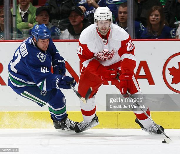Kyle Wellwood of the Vancouver Canucks checks Drew Miller of the Detroit Red Wings during the game at General Motors Place on March 20, 2010 in...