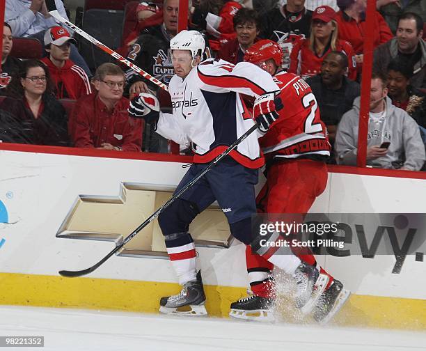 Joni Pitkanen of the Carolina Hurricanes takes a hit along the boards from Eric Fehr of the Washington Capitals during the NHL game on March 18, 2010...