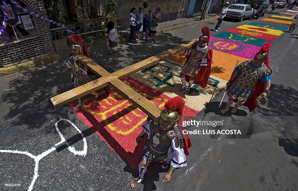 Actors carry a cross by a sawdust carpet