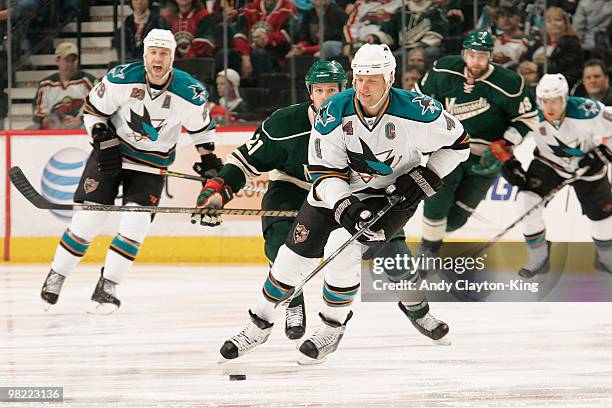 Rob Blake of the San Jose Sharks skates with the puck while Kyle Brodziak of the Minnesota Wild defends during the game at the Xcel Energy Center on...