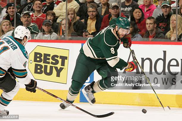 Brent Burns of the Minnesota Wild skates with the puck wwith Raitis Ivanans of the San Jose Sharks defending during the game at the Xcel Energy...