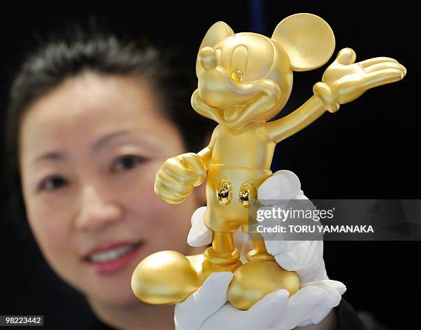 An employee of Mitsukoshi Department Store intoduces a pure gold Mickey Mouse at the head store in Tokyo on April 3, 2010. The department store...