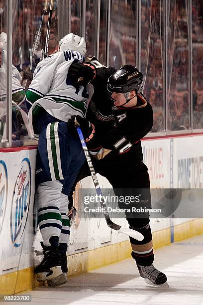 Corey Perry of the Anaheim Ducks checks Kyle Wellwood of the Vancouver Canucks into the boards during the game on April 2, 2010 at Honda Center in...