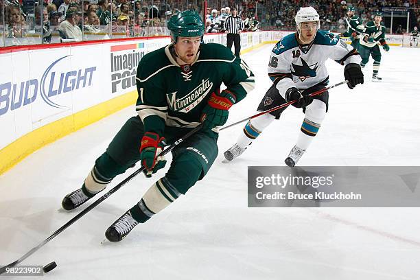 Kyle Brodziak of the Minnesota Wild skates with the puck while Devin Setoguchi of the San Jose Sharks defends during the game at the Xcel Energy...