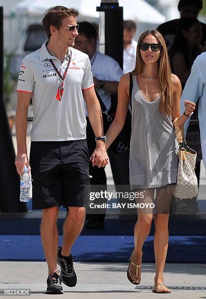 McLaren-Mercedes driver Jenson Button of Britain walks with his girlfriend Jessica Michibata on the paddock prior to the third practice session for...