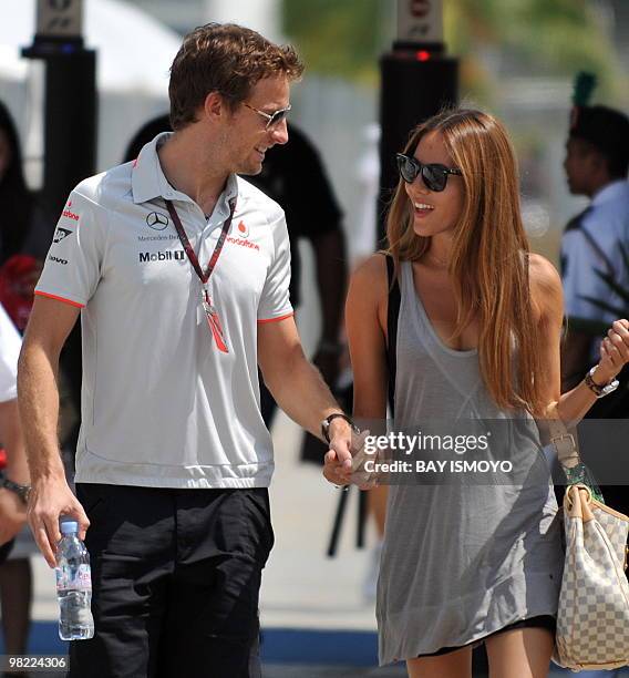 McLaren-Mercedes driver Jenson Button of Britain walks with his girlfriend Jessica Michibata on the paddock prior to the third practice session for...