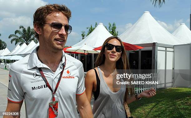 McLaren-Mercedes driver Jenson Button of Britain walks with his girlfriend Jessica Michibata on the paddock prior to the third practice session for...