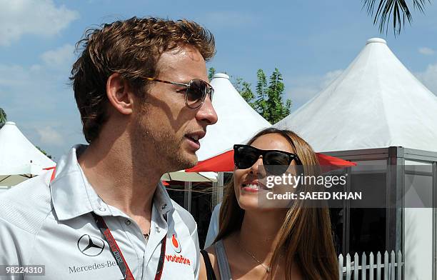 McLaren-Mercedes driver Jenson Button of Britain walks with his girlfriend Jessica Michibata on the paddock prior to the third practice session for...