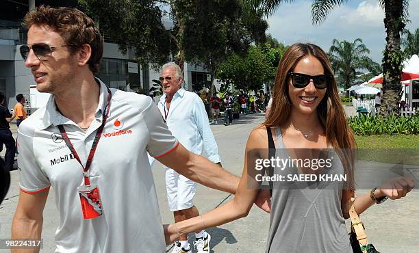 McLaren-Mercedes driver Jenson Button of Britain turns right for pit land while his his girlfriend Jessica Michibata walk towards hospitality booth...