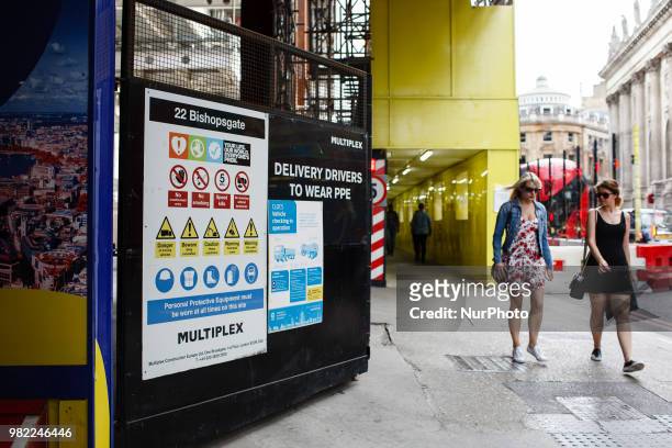 Pedestrians walk past a site entrance to the under-construction 22 Bishopsgate tower, marketed as Twentytwo, as the building continues to rise to its...