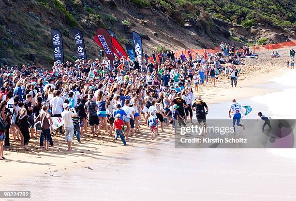 Kelly Slater of the United States of America runs up the beach as the crowd chases him during the Rip Curl Pro Bells Beach on April 3, 2010 in Bells...