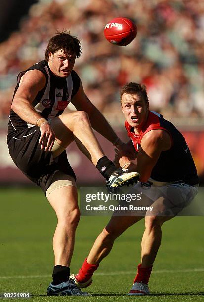 Leigh Brown of the Magpies kicks whilst being tackled by Clint Bartram of the Demons during the round two AFL match between the Collingwood Magpies...