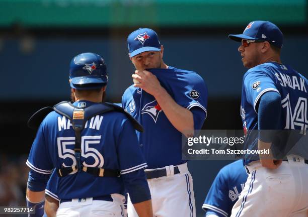 Happ of the Toronto Blue Jays waits on the mound moments before being relieved in the ninth inning as Russell Martin and Justin Smoak look on during...