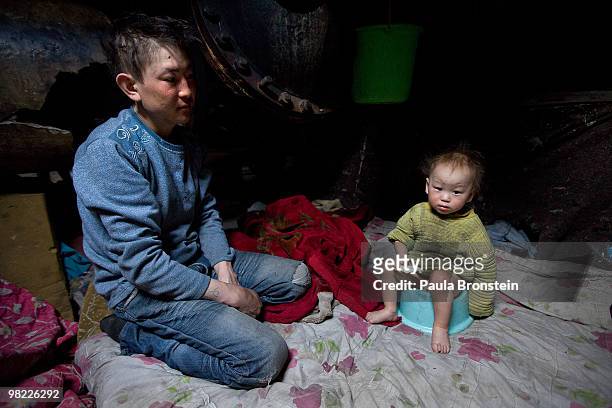 Baigalnaa sits along side his son Munkhorgil, 18 months old while he sits on a baby toilet seat inside the small sewer wher the family lives March...